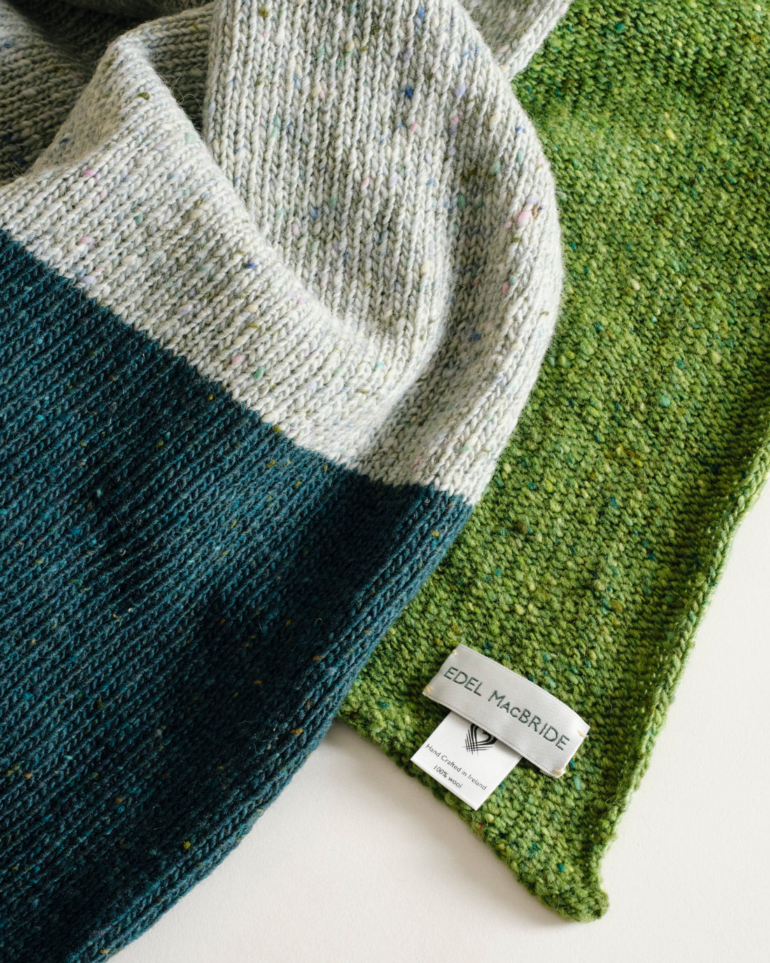 Three knitted scarves in gray, blue, and green on a light background